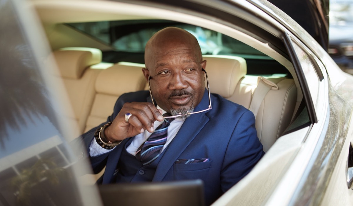 A suited passenger seated in the back of a car